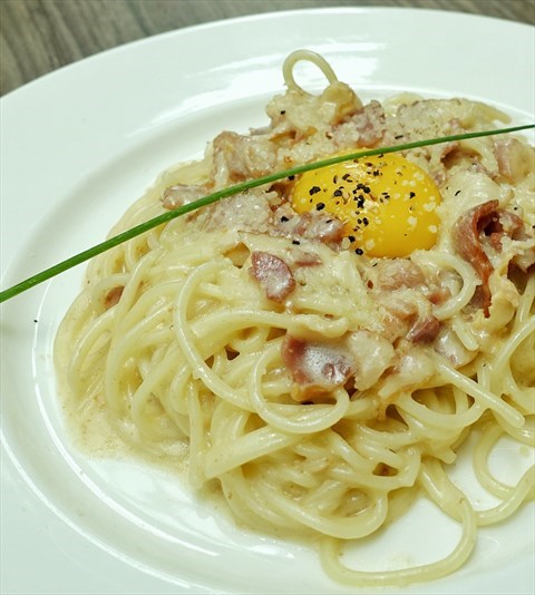 Freshly made spaghetti with bacon, egg, creamy sauce and sprinkled with parmesan cheese . 