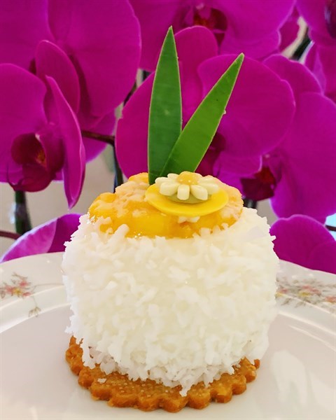 With D24 mousse & coconut sponge enrobed in coconut mousse as well as a mirror glaze coated with coconut flakes on top of a coconut biscuit, adorned with diced mango, mango jelly & chocolate leaves.